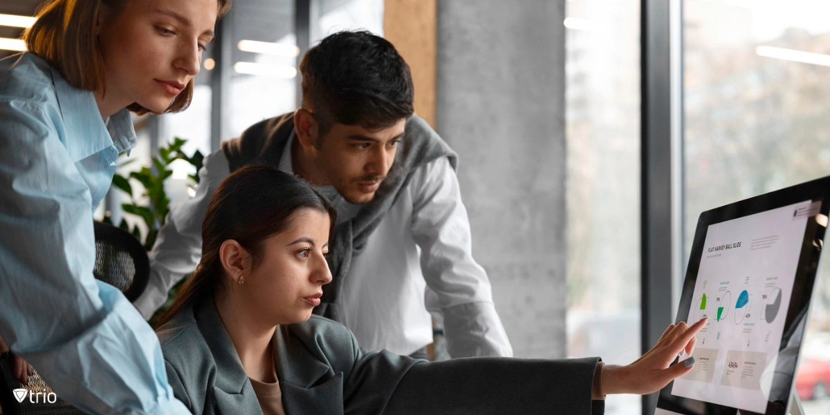 Employee explainingsomething in front of a computer to two other employees