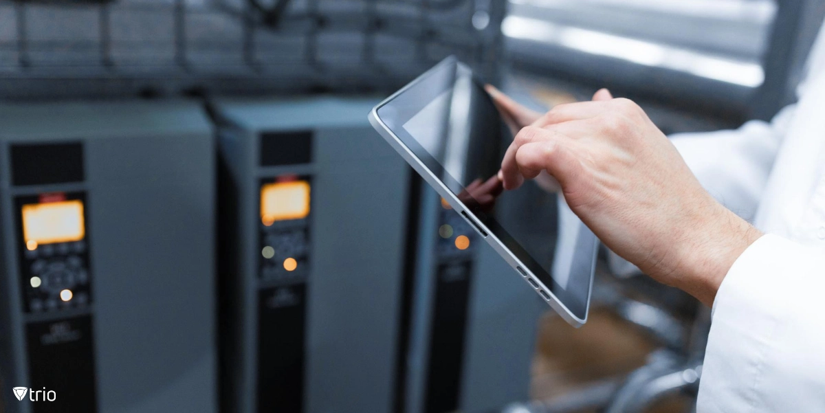 Eine Person steht vor Computerservern und hält ein Tablet. 