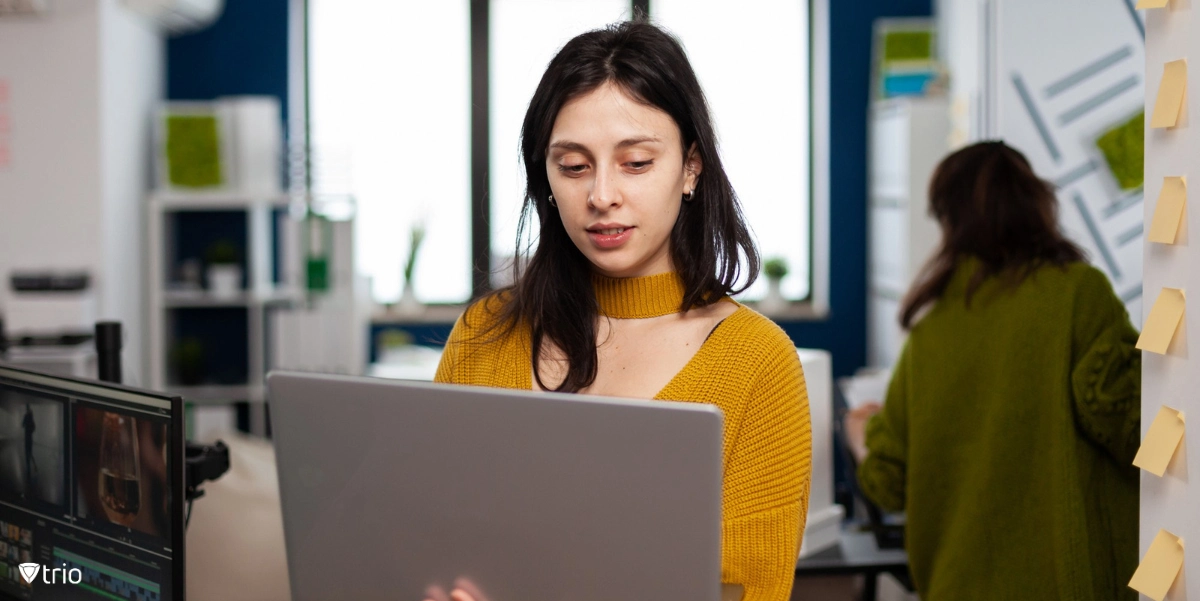 Woman using a laptop in her office around other employees