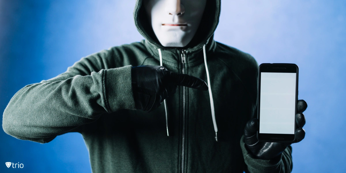 Ein Mann mit Maske zeigt auf ein Mobilgerät.