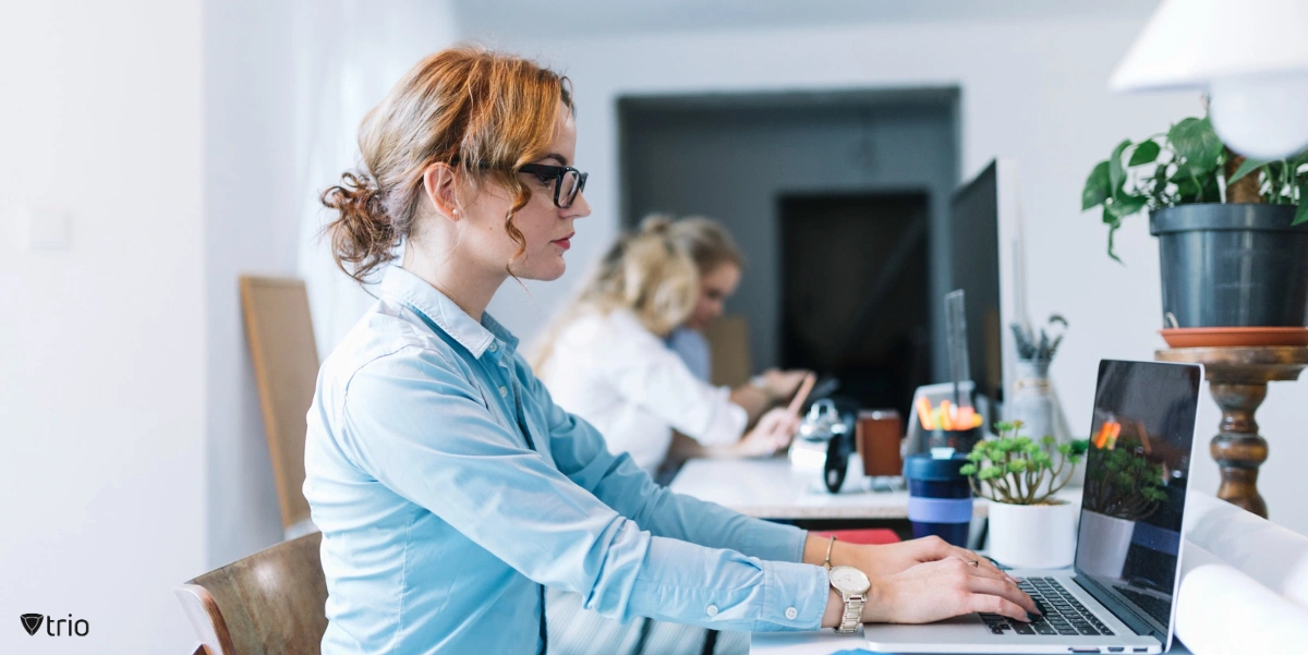 Three young businesswomen sitting at workplace talking to each other in the office