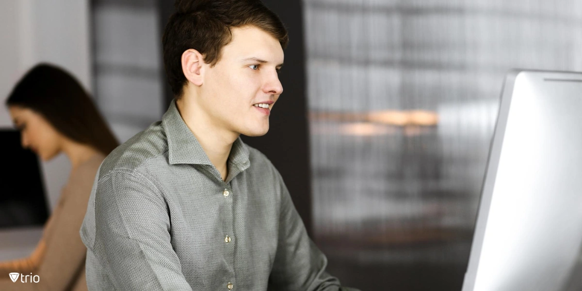 Dark-haired young businessman and programmer in a green shirt is working hard on his computer