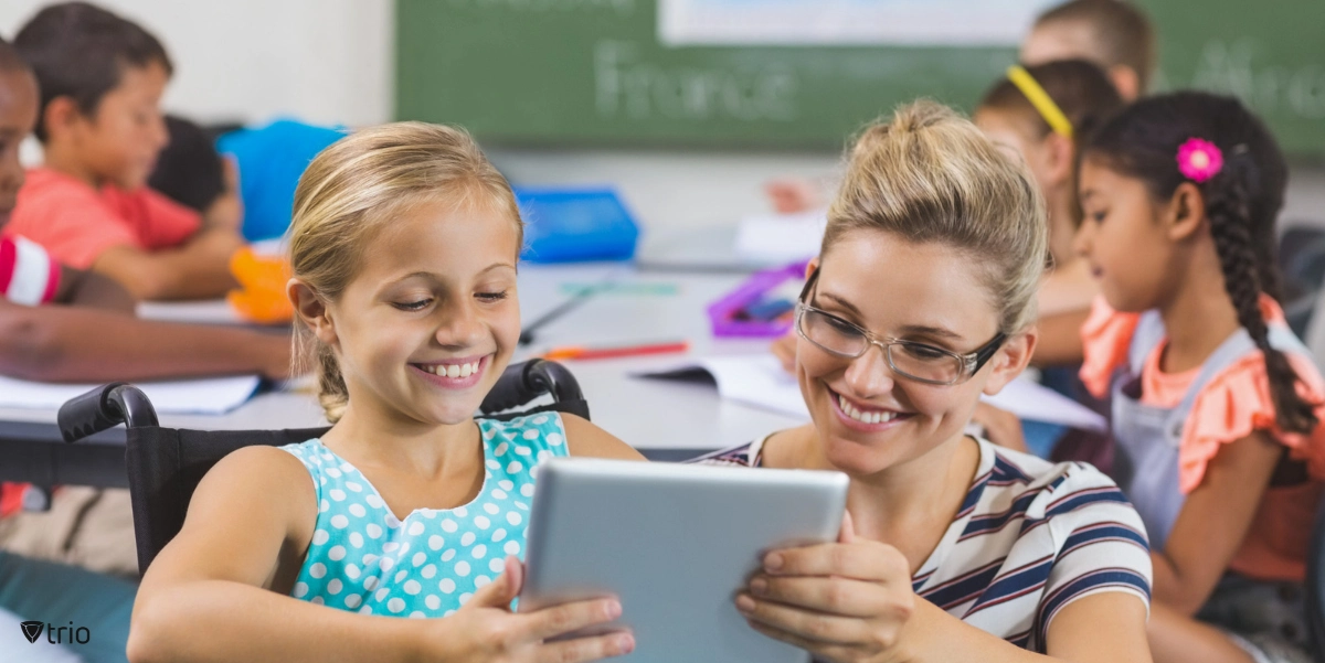 Schoolgirl and teacher using digital tablet in classroom