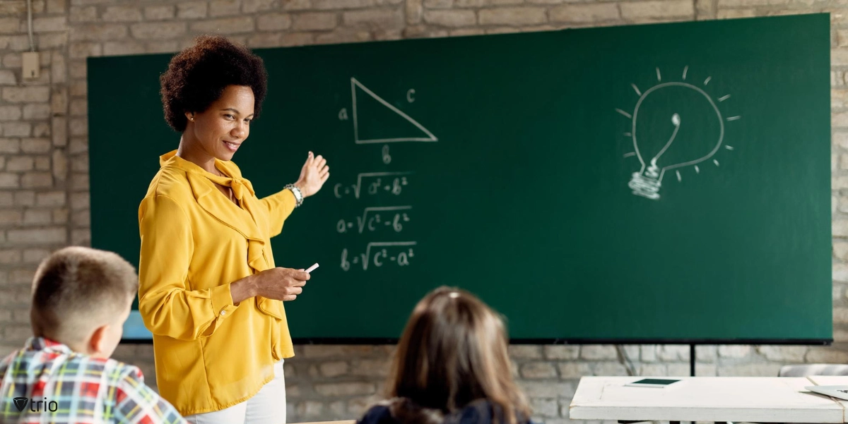 Happy teacher teaching elementary students math in the classroom