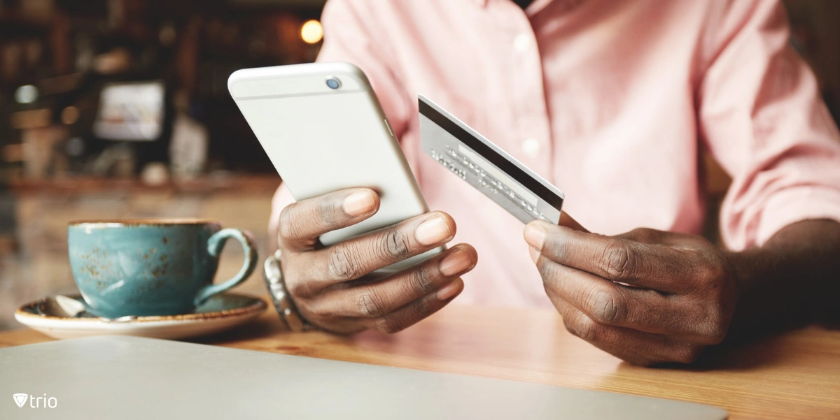 African American man in casual shirt paying with credit card online while making orders