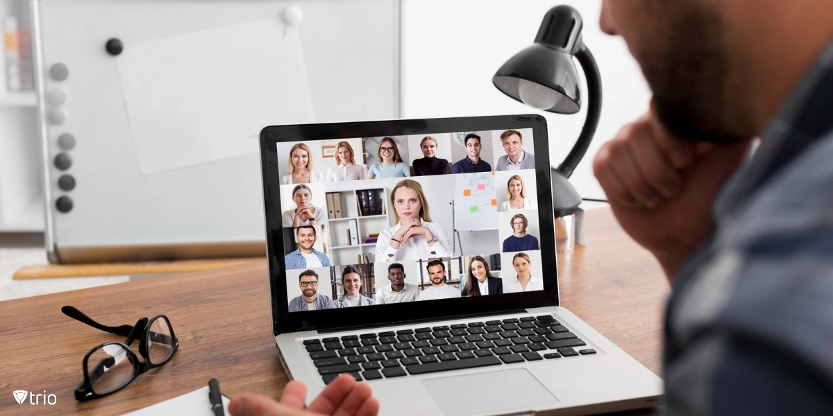 Eine Person nimmt an einem Zoom-Meeting teil. Auf einem Laptop-Bildschirm werden mehrere Teilnehmer einer virtuellen Telefonkonferenz angezeigt.