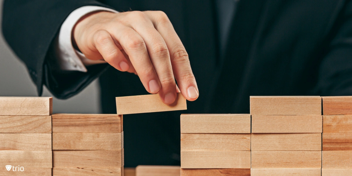 Nahaufnahme einer Person, die Holzwürfel auf einem Tisch anordnet, die Konzepte des Risikomanagements, der Entscheidungsfindung und der Strategieplanung symbolisieren