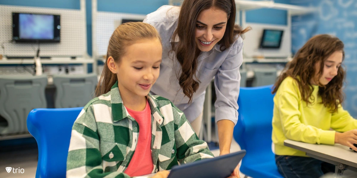 Lehrerin schaut in Tablet eines Mädchens in der Schule