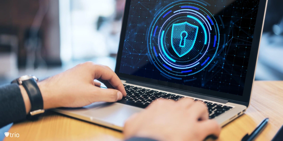 hands of businessman using laptop with glowing blue shield on screen