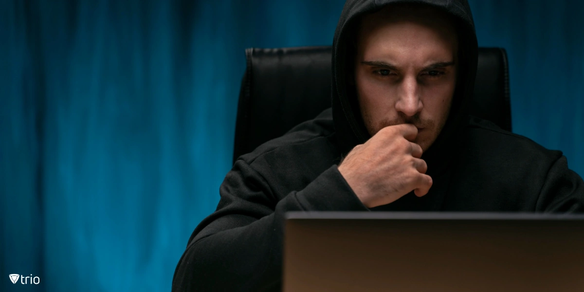 Ein verdächtiger Typ in einem schwarzen Kapuzenpulli, der auf einen Laptop-Monitor schaut
