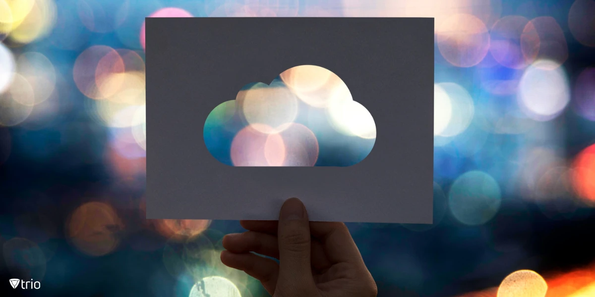 A perforated paper cutout shaped like a cloud with a smooth, rounded design, with a blurry background of different lights.
