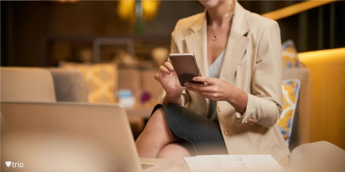 Geschäftsfrau benutzt ihr Telefon, während sie einen Laptop auf ihrem Schreibtisch hat
