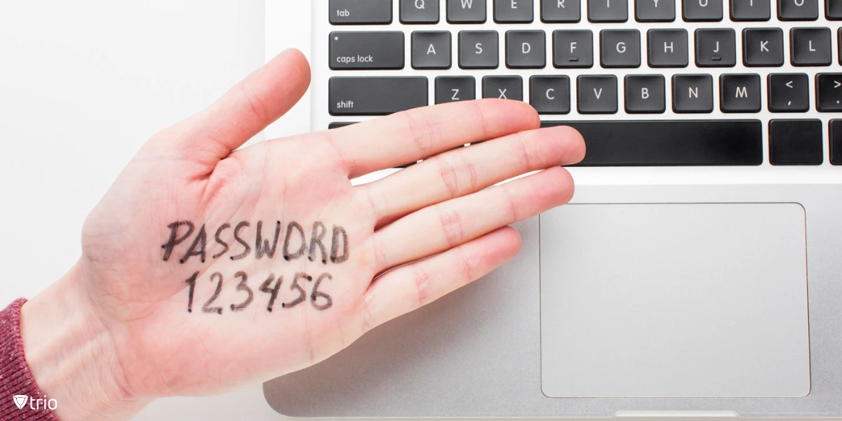 Eine Hand mit dem Wort „PASSWORT“ und den Zahlen „123456“ auf der Handfläche, platziert über der Tastatur eines Laptops.