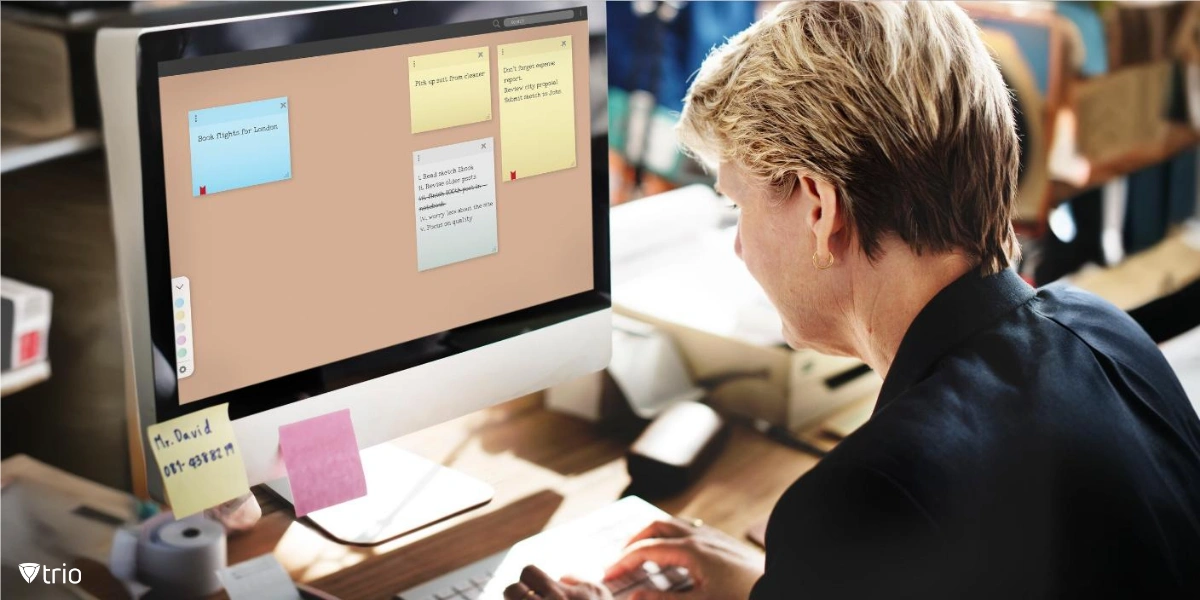 Eine Person sitzt an einem Computer und betrachtet digitale Haftnotizen, die auf einem großen Monitor angezeigt werden