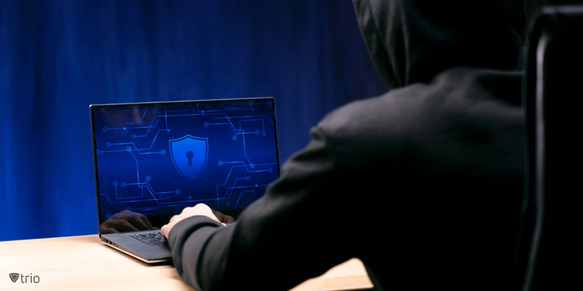Mann mit Kapuzenpulli sitzt vor Laptop mit Schild und Sperre auf dem Bildschirm
