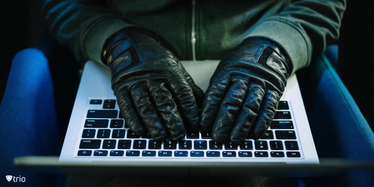 A person wearing black leather gloves typing on a laptop keyboard