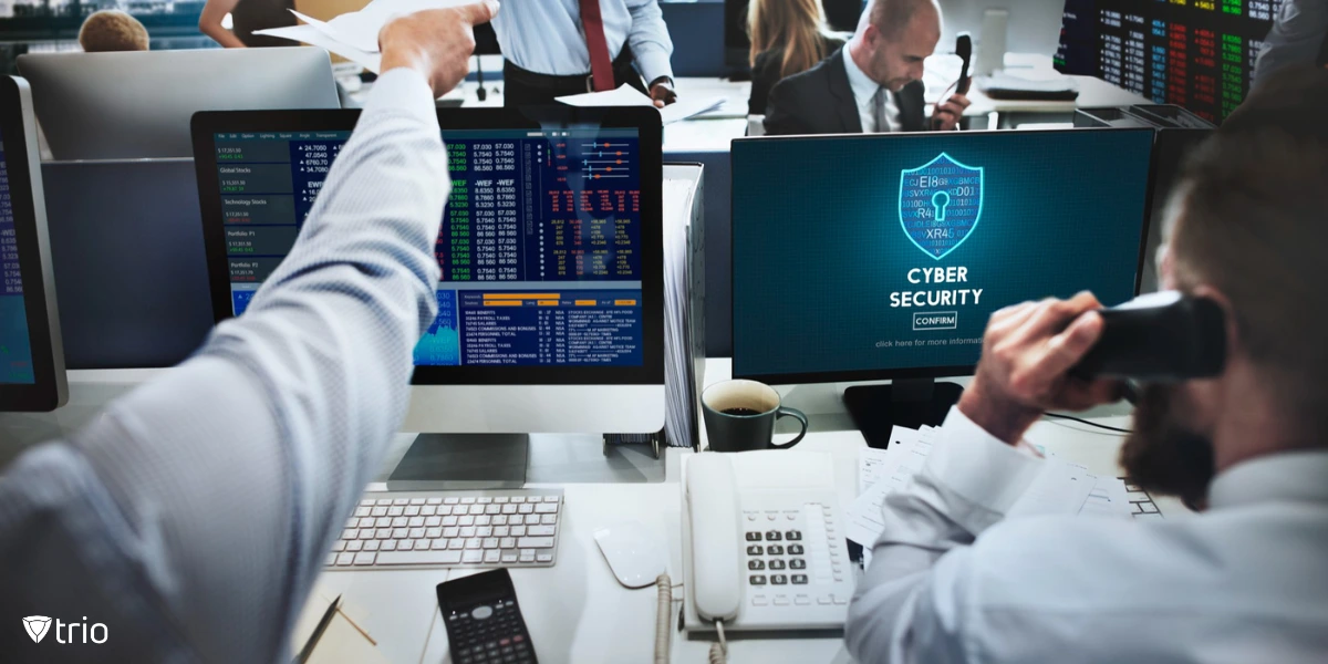 A busy financial office with employees engaged in trading activities, while one computer screen prominently displays a cybersecurity alert