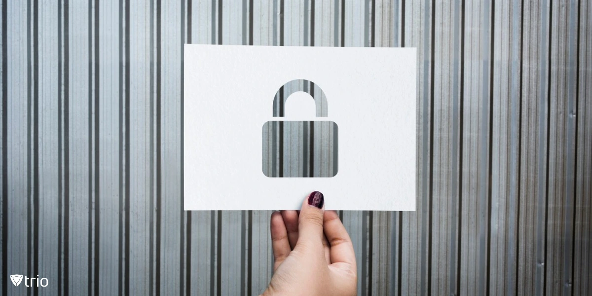 A hand holds a white piece of paper with a cutout of a padlock symbol, placed against a metallic, vertically striped background
