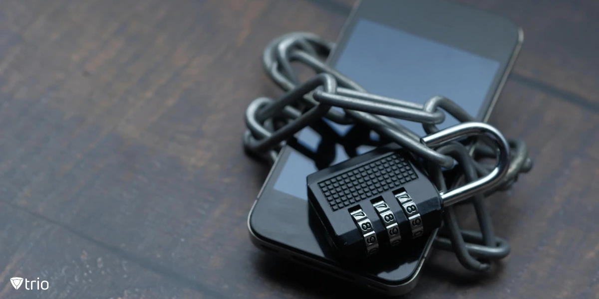 A smartphone is tightly wrapped in metal chains, secured by a combination lock.
