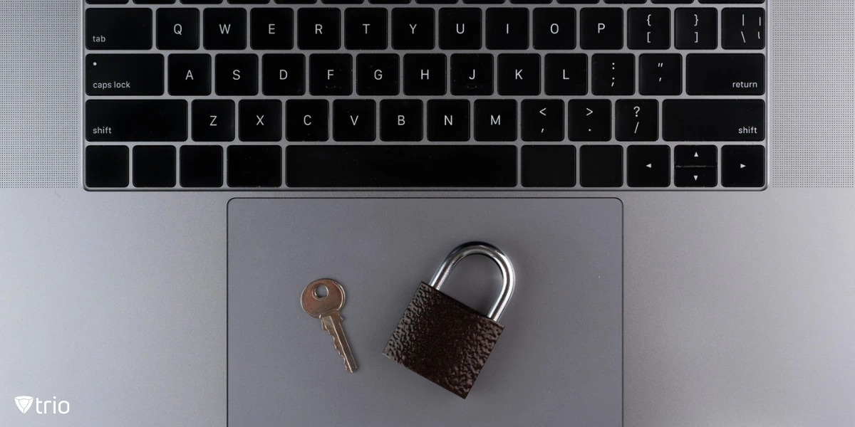 A sleek, modern laptop sits on a desk, with a sturdy padlock and key resting on its trackpad.